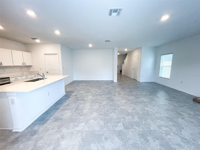 kitchen with a sink, visible vents, open floor plan, and white cabinets