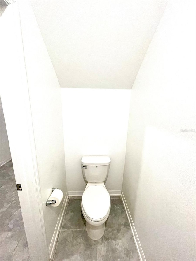 bathroom featuring lofted ceiling, toilet, and baseboards