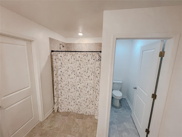 bathroom featuring baseboards, toilet, and a shower with curtain