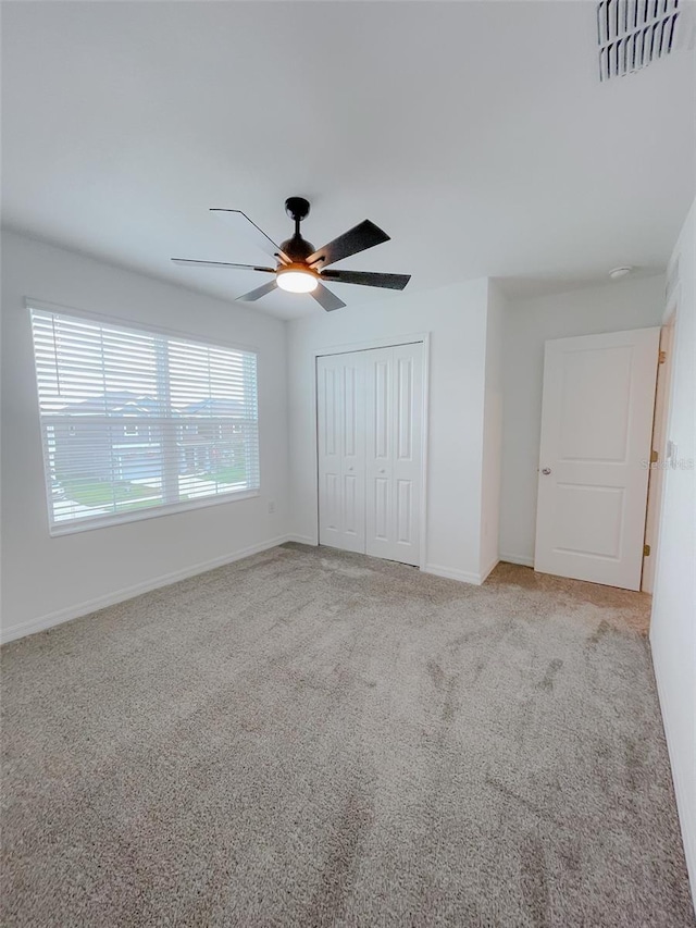 unfurnished bedroom featuring baseboards, visible vents, ceiling fan, a closet, and carpet flooring