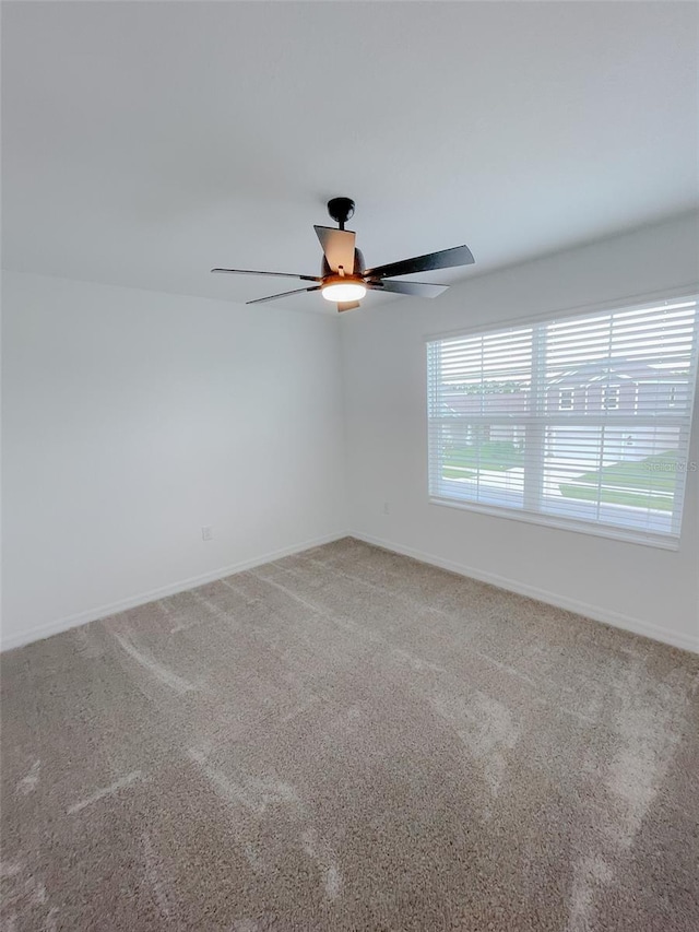 spare room featuring baseboards, carpet floors, and ceiling fan