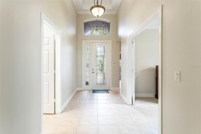 entryway featuring light tile patterned floors, crown molding, and a high ceiling