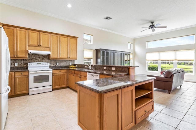 kitchen with kitchen peninsula, dark stone counters, ornamental molding, white appliances, and ventilation hood