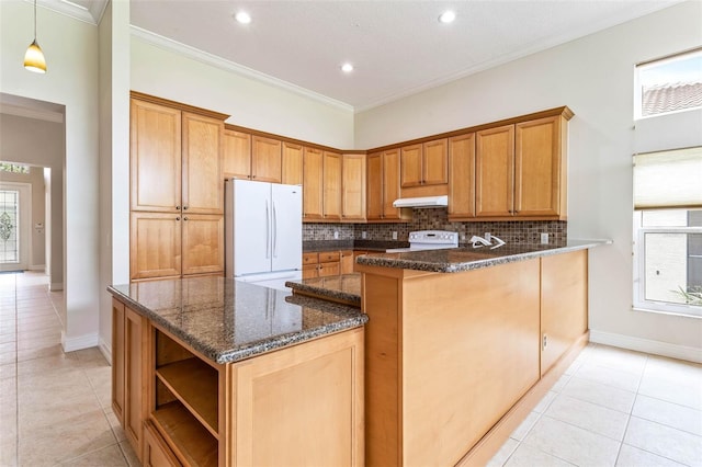 kitchen with kitchen peninsula, crown molding, dark stone countertops, white appliances, and light tile patterned floors