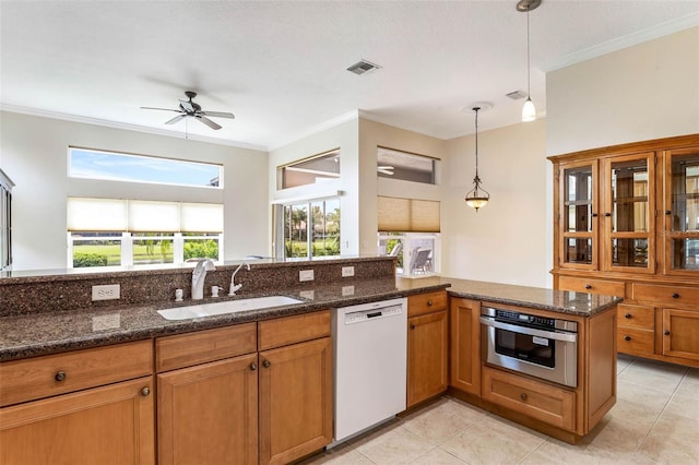 kitchen with stainless steel oven, sink, white dishwasher, dark stone counters, and pendant lighting