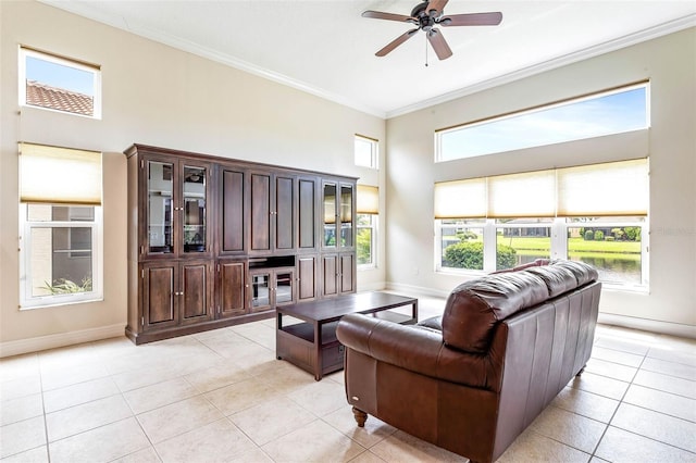 tiled living room featuring ceiling fan, a high ceiling, and ornamental molding