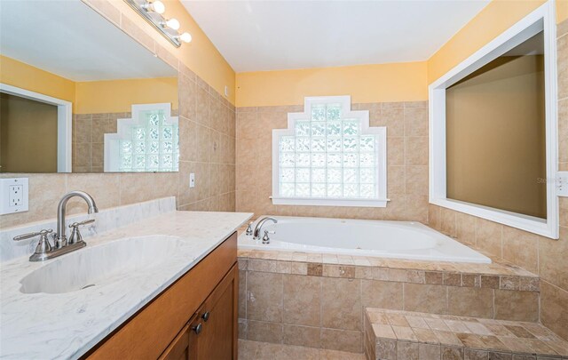 bathroom featuring tile walls, tiled tub, and vanity