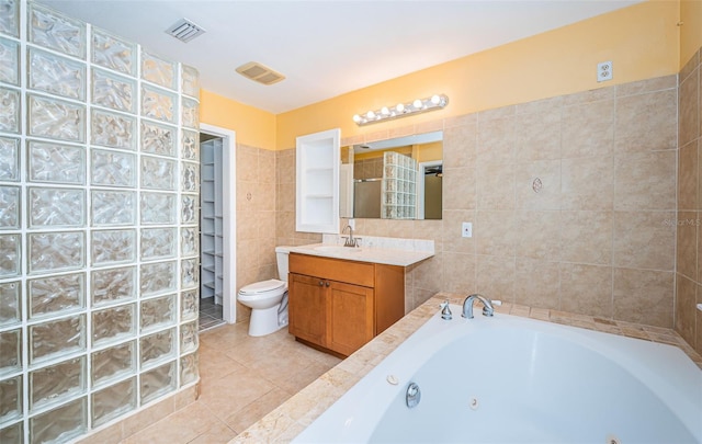 bathroom featuring vanity, toilet, a bath, tile walls, and tile patterned flooring