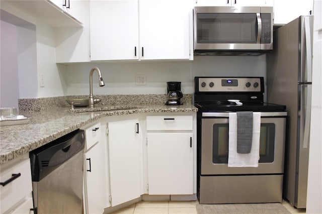 kitchen featuring appliances with stainless steel finishes, light stone counters, sink, light tile patterned floors, and white cabinets