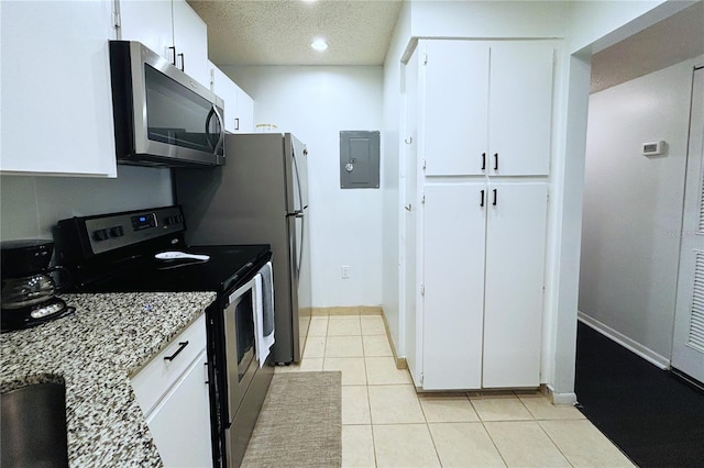 kitchen featuring electric panel, white cabinets, light tile patterned floors, appliances with stainless steel finishes, and light stone counters