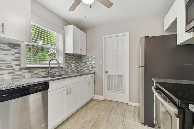 kitchen featuring appliances with stainless steel finishes, sink, white cabinetry, and ceiling fan