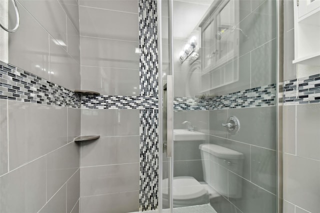 bathroom featuring a shower with shower door, toilet, and tile walls