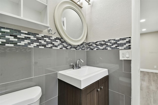 bathroom with vanity, toilet, decorative backsplash, and hardwood / wood-style flooring