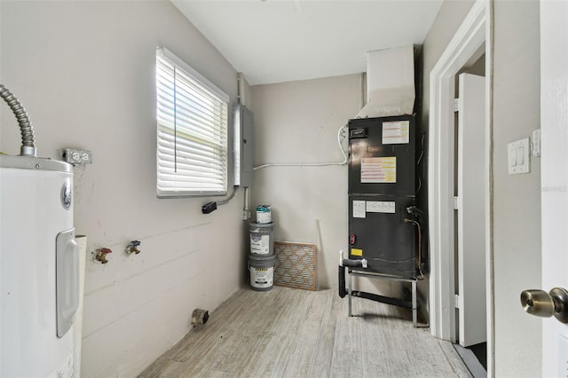 utility room with electric water heater, heating unit, and electric panel