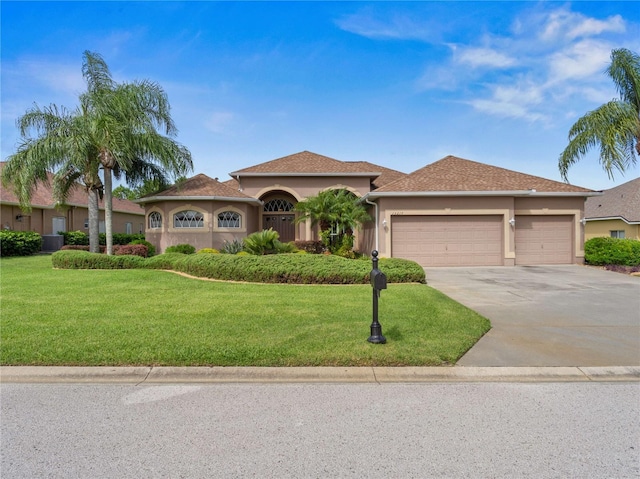 view of front facade with stucco siding, a front lawn, concrete driveway, and a garage