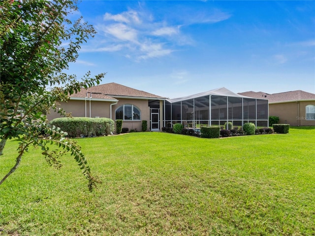 rear view of house featuring a yard, a sunroom, and stucco siding