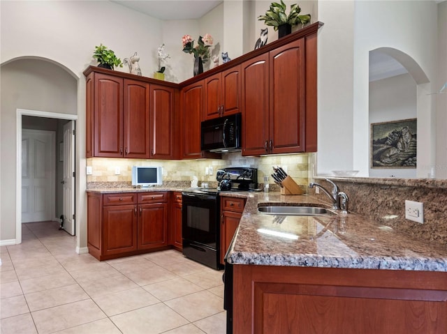 kitchen with decorative backsplash, black appliances, stone countertops, and a sink