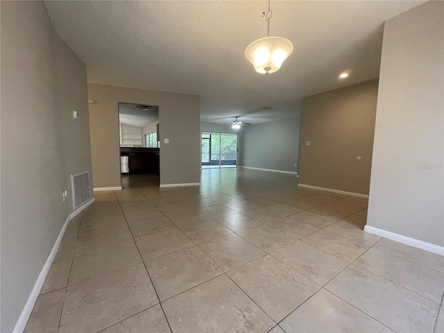 tiled spare room with a textured ceiling and ceiling fan