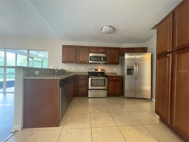 kitchen featuring dark stone countertops, appliances with stainless steel finishes, light tile patterned floors, and sink