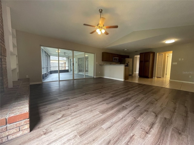 unfurnished living room with wood-type flooring, vaulted ceiling, and ceiling fan