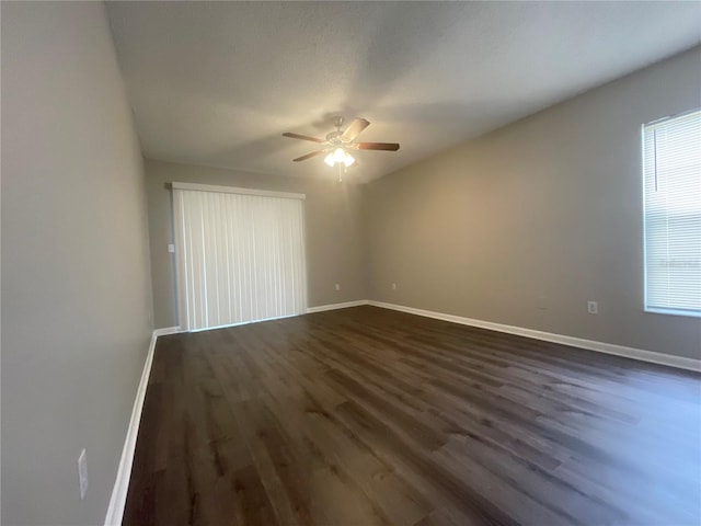 spare room featuring ceiling fan, dark wood-type flooring, and a wealth of natural light