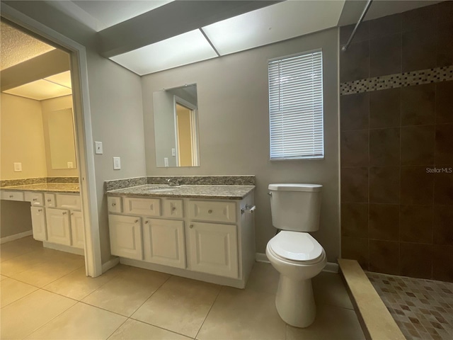 bathroom featuring a tile shower, tile patterned flooring, vanity, and toilet