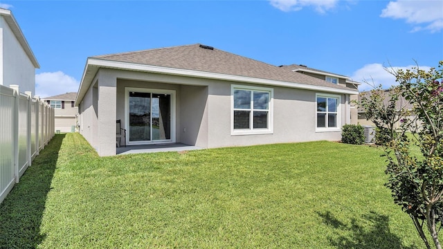 7774 Sail Clover Ln, Zephyrhills, FL 33540 - back of property with fence, stucco siding, a yard, and a shingled roof