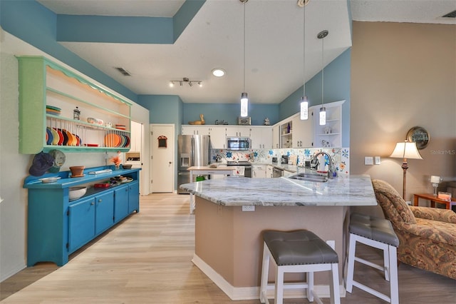 kitchen featuring backsplash, kitchen peninsula, decorative light fixtures, a breakfast bar area, and appliances with stainless steel finishes