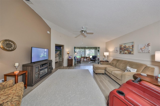 living room with hardwood / wood-style flooring, ceiling fan, lofted ceiling, and a textured ceiling