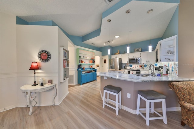 kitchen featuring appliances with stainless steel finishes, sink, decorative light fixtures, white cabinetry, and a breakfast bar area