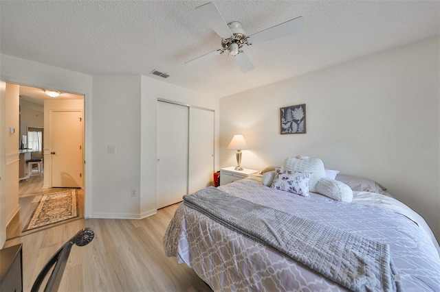 bedroom featuring ceiling fan, a closet, a textured ceiling, and light wood-type flooring