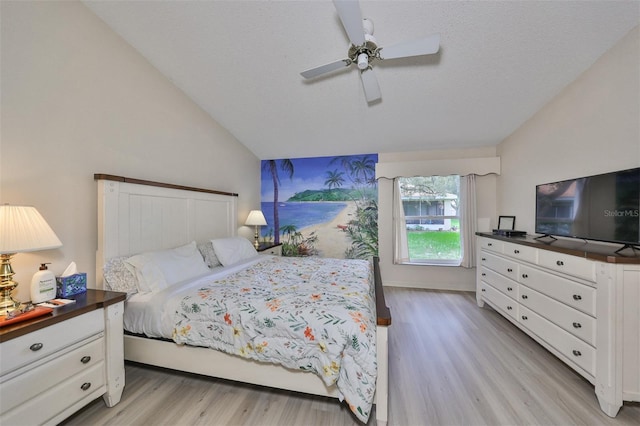 bedroom with a textured ceiling, ceiling fan, light hardwood / wood-style flooring, and vaulted ceiling