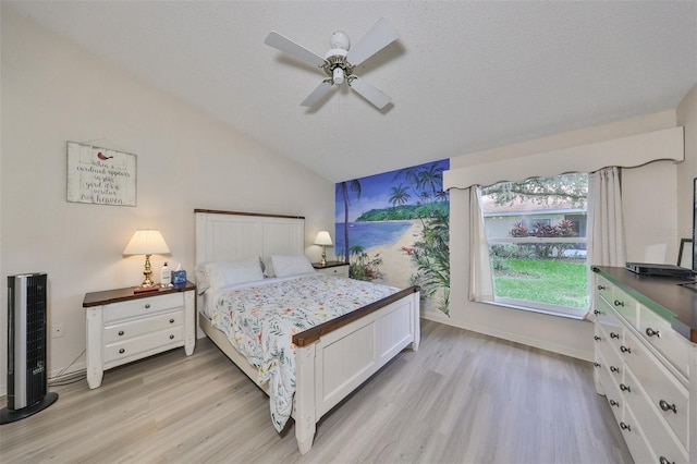 bedroom with ceiling fan, vaulted ceiling, a textured ceiling, and light hardwood / wood-style flooring