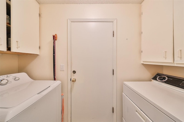 laundry area featuring cabinets, a textured ceiling, and washing machine and clothes dryer