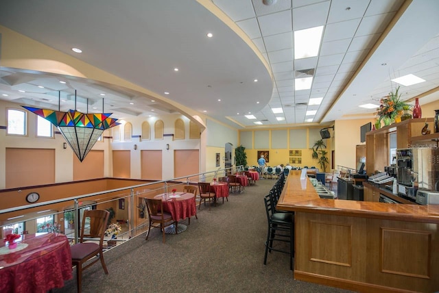 interior space with a paneled ceiling and dark carpet