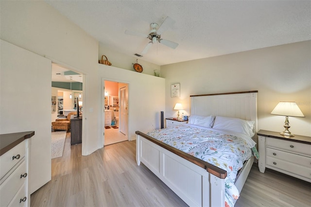 bedroom with ceiling fan, light hardwood / wood-style flooring, ensuite bathroom, and a textured ceiling