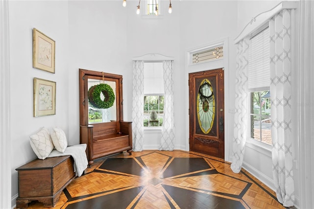 foyer entrance with a towering ceiling and parquet flooring