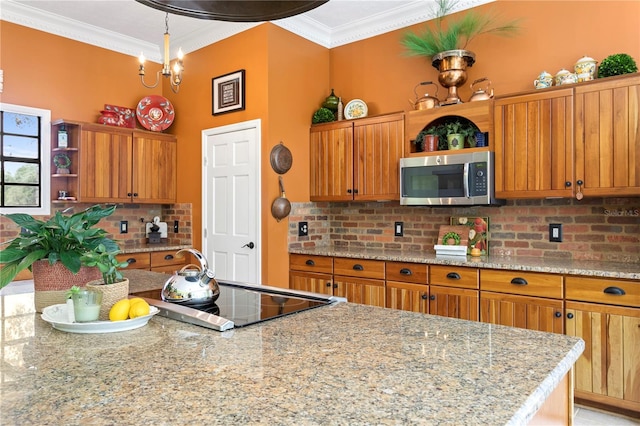 kitchen with black electric cooktop, decorative backsplash, light stone countertops, crown molding, and a chandelier