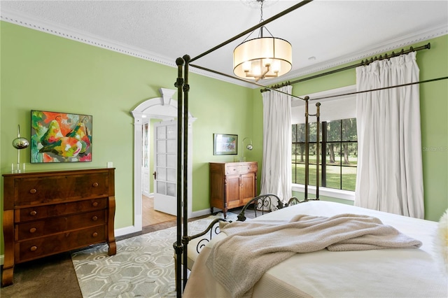 bedroom with a textured ceiling, carpet flooring, ornamental molding, and ensuite bath