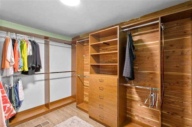 walk in closet with light hardwood / wood-style floors