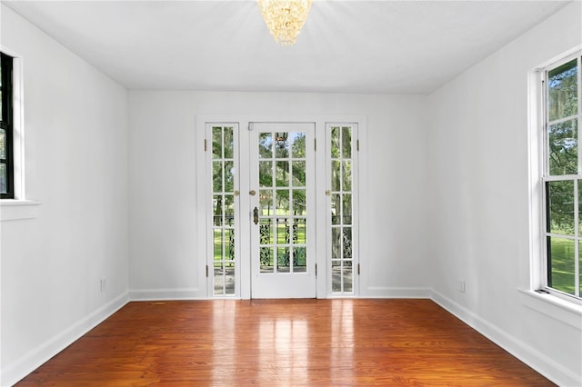 empty room featuring an inviting chandelier and hardwood / wood-style flooring