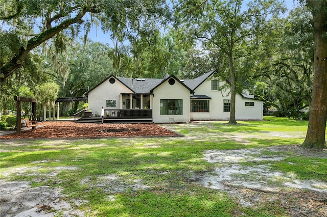 rear view of house with a wooden deck and a lawn