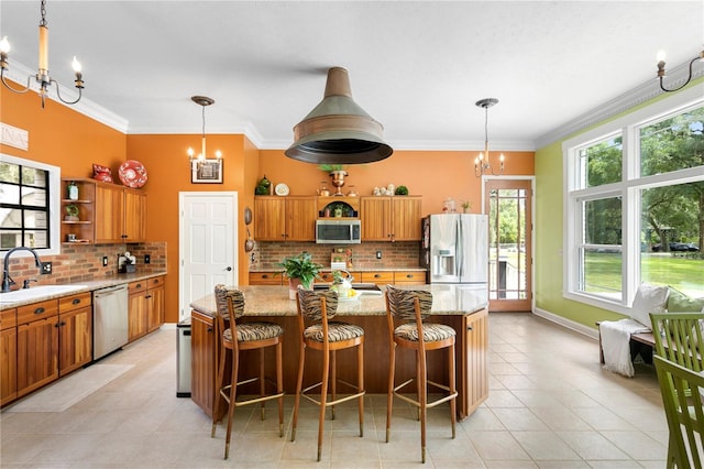 kitchen featuring decorative backsplash, pendant lighting, stainless steel appliances, crown molding, and a center island