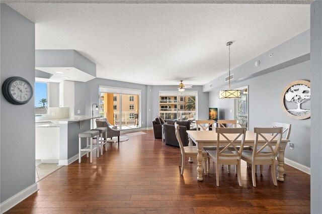 dining space with dark wood-type flooring, a textured ceiling, and ceiling fan