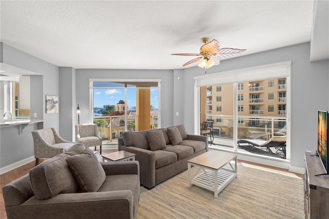 living room featuring a textured ceiling, light hardwood / wood-style flooring, and ceiling fan