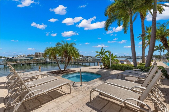 view of pool with a water view, a patio, and a hot tub