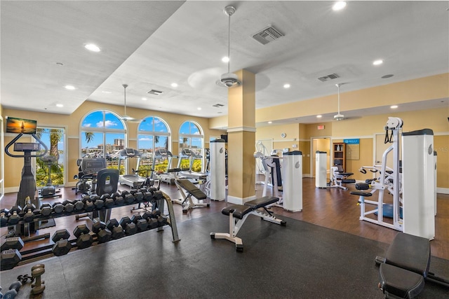 workout area featuring decorative columns, dark hardwood / wood-style flooring, and ceiling fan