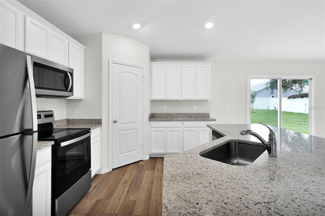 kitchen with appliances with stainless steel finishes, light stone counters, dark hardwood / wood-style flooring, white cabinetry, and sink