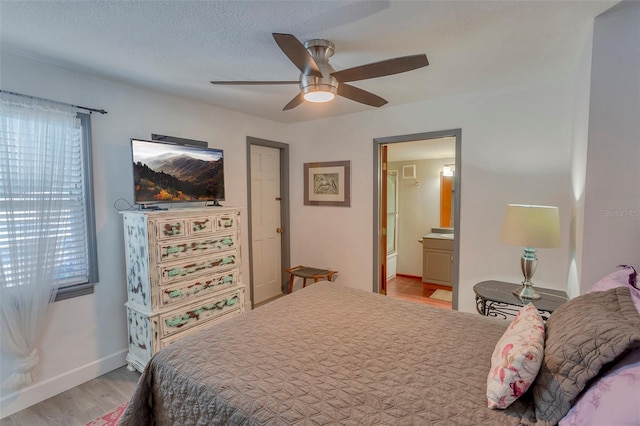 bedroom featuring ceiling fan, connected bathroom, a textured ceiling, and light hardwood / wood-style flooring