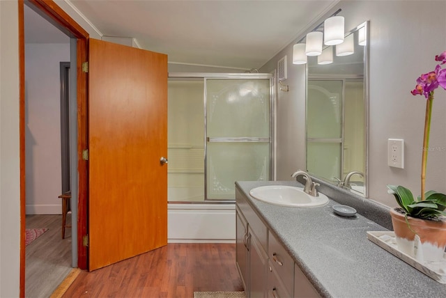 bathroom featuring vanity, hardwood / wood-style floors, and combined bath / shower with glass door